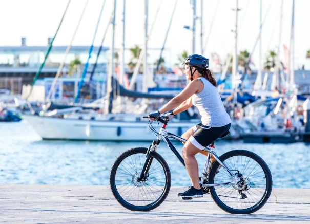 Woman riding her bike beside a marina.