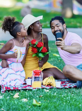 A young family having a picnic and taking a selfie.