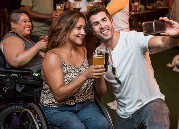 A woman in a wheelchair smiling taking a selfie with a man.